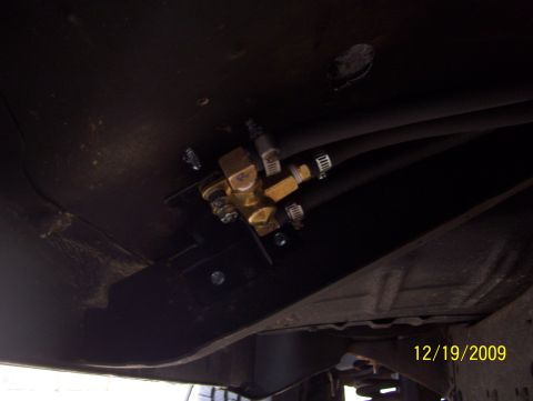 1978 Ford Bronco - Close-up view of a fuel line valve assembly mounted to the underside of a vehicle.