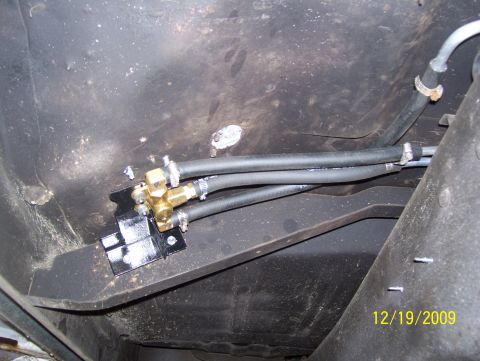 1978 Ford Bronco - Close-up of a fuel line valve assembly installed on a vehicle's undercarriage.