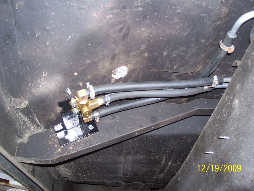 Fuel line valve assembly mounted to vehicle frame with hoses attached