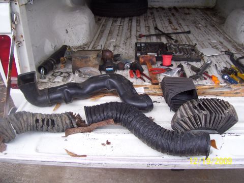 1978 Ford Bronco - Various vehicle parts and tools are laid out in the bed of a pickup truck.