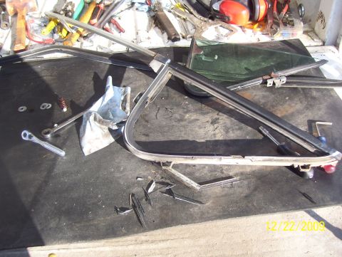 1978 Ford Bronco - Window frame and associated parts laid out on a workbench, along with various tools for repair or disassembly.