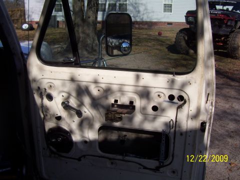 1978 Ford Bronco - View of a disassembled truck door interior with another vehicle in the background.
