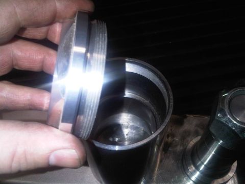 1996 Ford Bronco - A hand holds a threaded cap over a matching metal cylinder, revealing internal threading.