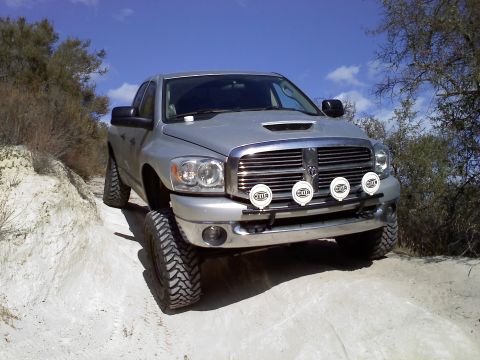 2006 Dodge 2500 - Silver 2006 Dodge 2500 pickup truck with auxiliary lights driving on a dirt road.