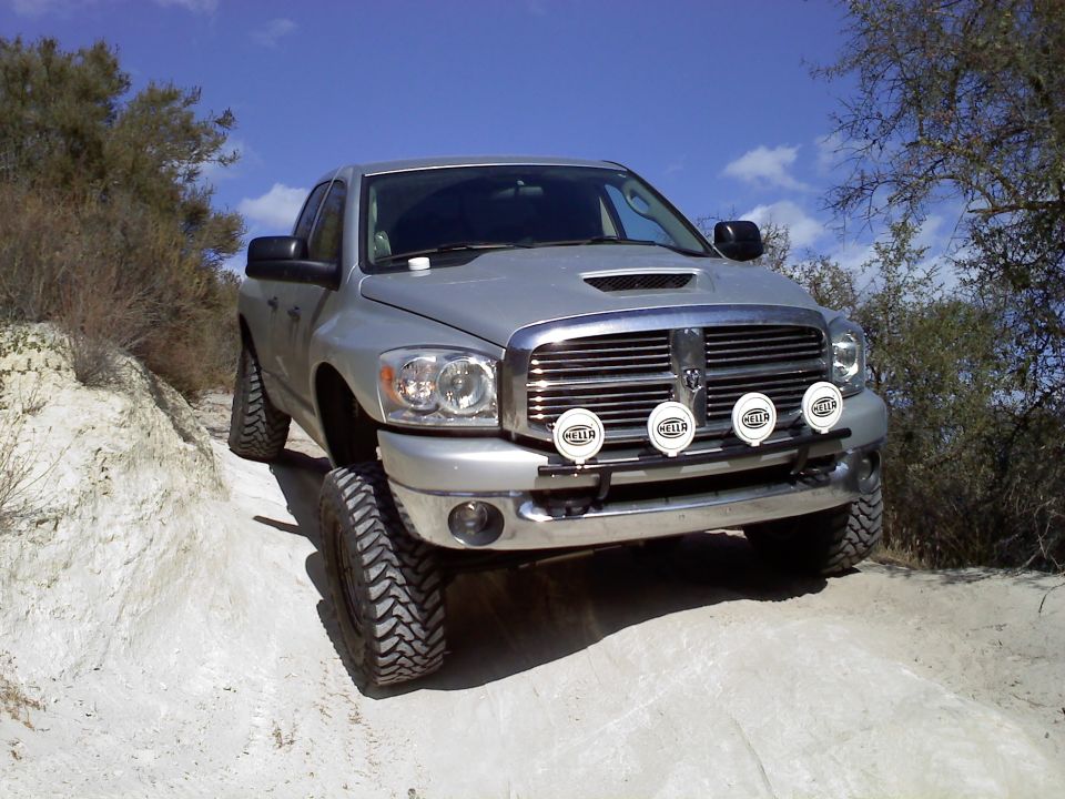 Silver 2006 Dodge 2500 pickup truck with auxiliary lights on a dirt road