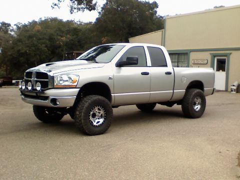 2006 Dodge 2500 - This lifted Dodge 2500 pickup truck is parked in front of a commercial building with trees in the background.