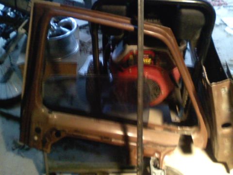 1990 Ford Bronco - A partial view of a vehicle's interior shows a door frame and a red engine part.
