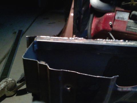 1990 Ford Bronco - Close-up of a cut metal panel, likely a vehicle body part, with a red engine component in the background.