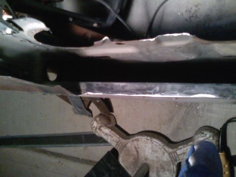 1990 Ford Bronco - Vehicle undercarriage detail, supported by a jack for maintenance or repair.