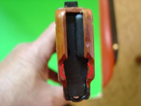 2000 Ford Crown Victoria - Close-up of a wooden gun grip with red markings, held by a hand.