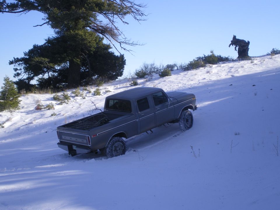 Crew cab pickup truck driving up a snowy hill