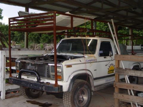 1996 Ford Bronco - This older model Ford pickup truck has a custom metal rack structure built over its cab and bed.