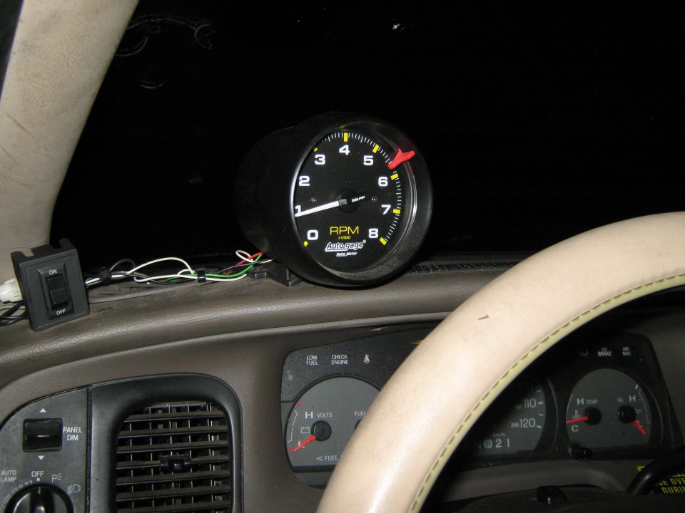 Tachometer gauge and dashboard interior with a steering wheel