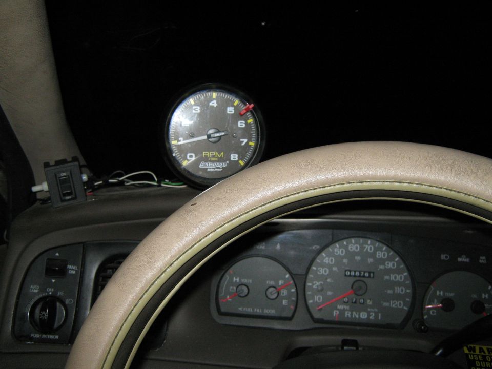 Dashboard interior with aftermarket tachometer above factory speedometer and fuel gauge