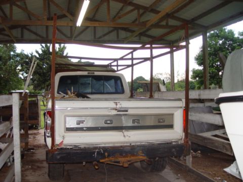 1996 Ford Bronco - Rear view of a white Ford pickup truck, likely from the late 1970s, parked under a covered structure.