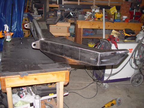 1993 Ford Bronco - A fabricated steel bumper sits on a workbench in a cluttered garage, ready for installation.