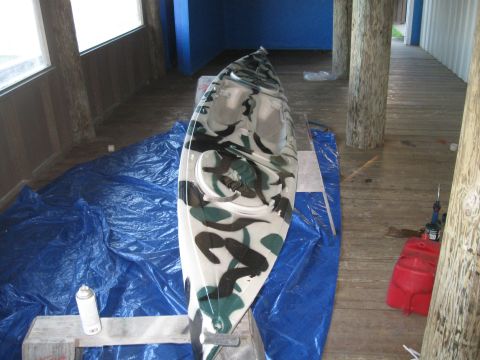 1991 Ford Bronco - A kayak with a camouflage paint scheme is positioned on a wooden deck, covered by blue tarps.