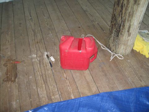 1991 Ford Bronco - A red plastic gas can rests on a wooden floor, with a knife and other items nearby.