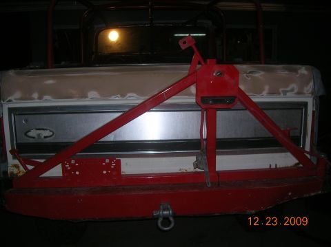 1985 Ford Bronco - The rear of a classic Ford Bronco shows a custom red bumper and tire carrier, with the tailgate undergoing preparation for paint.