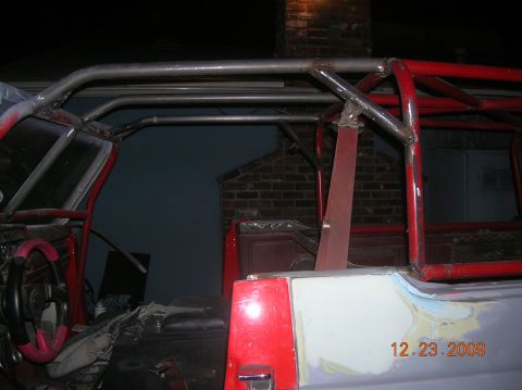 1985 Ford Bronco - This image shows the interior of a vehicle undergoing modifications, a prominent roll cage and a pink-trimmed steering wheel.