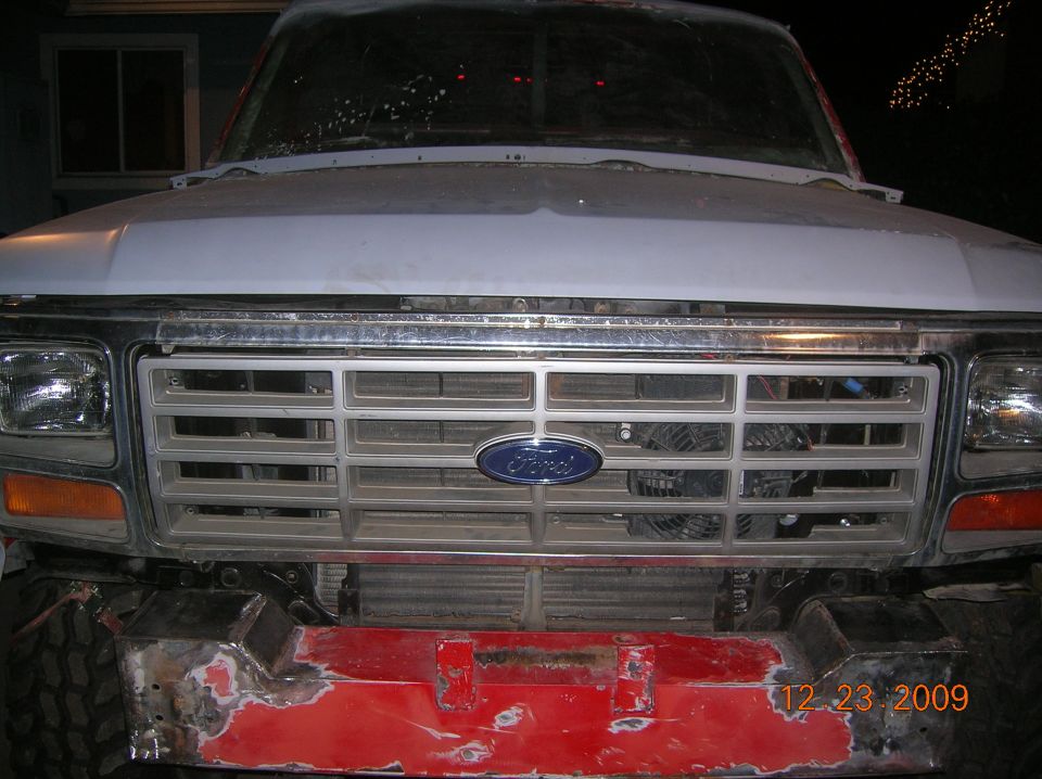 Front of a white Ford truck with a silver grille and a red, unfinished bumper. Date stamp reads 12 23 2009