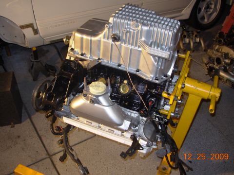 1991 Ford Taurus - Engine assembly sits on a yellow stand, with a portion of a car body visible in the background.