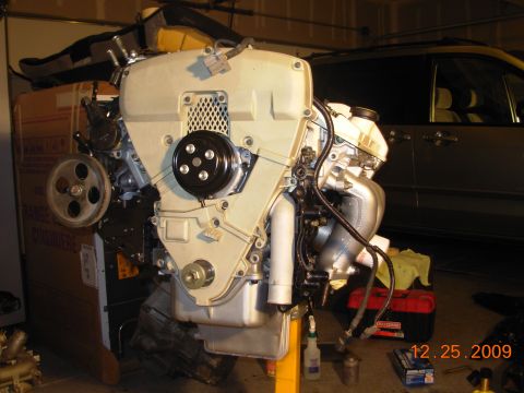 1991 Ford Taurus - Engine assembly displayed in a garage setting, with a vehicle visible behind it.
