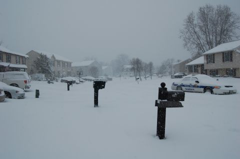 2002 BMW M3 - A snow-covered street with multiple vehicles and houses during a winter storm.