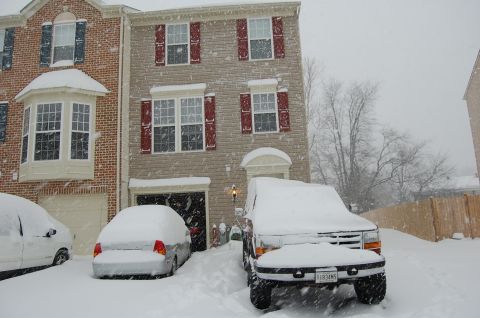 2002 BMW M3 - Two vehicles are parked in front of a snow-covered house during a winter storm.