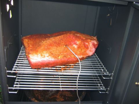 1992 Ford Bronco - Meat seasoned with rub and a thermometer inserted, resting on a rack inside a smoker.