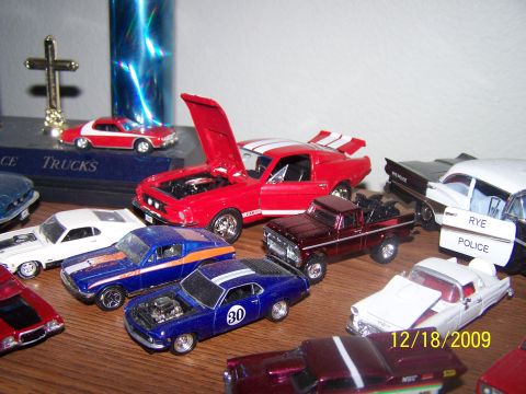 1972 Ford Ranchero - A display of multiple toy cars, a red Mustang and a blue muscle car with racing stripes.