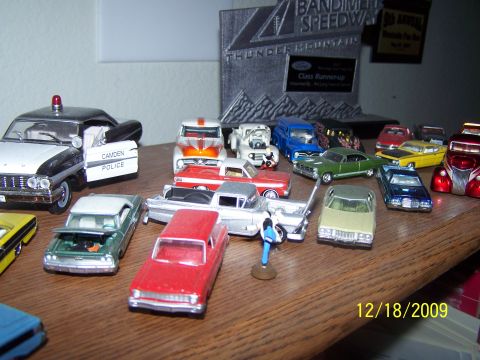 1972 Ford Ranchero - A variety of model cars are displayed on a wooden surface, with a trophy in the background.