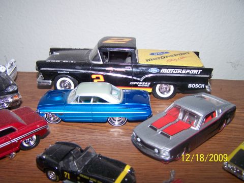 1972 Ford Ranchero - A collection of toy cars includes a black 1957 Ford Ranchero with racing livery and a blue two-door sedan.