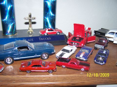1972 Ford Ranchero - A collection of various model cars is displayed on a wooden shelf, with trophies in the background.