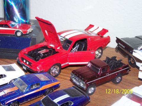 1972 Ford Ranchero - A collection of detailed model cars are displayed on a wooden surface, with a red Mustang prominently featured.