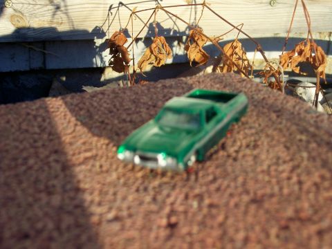 1972 Ford Ranchero - A green 1972 Ford Ranchero toy car sits on a gravel surface with dried leaves overhead.
