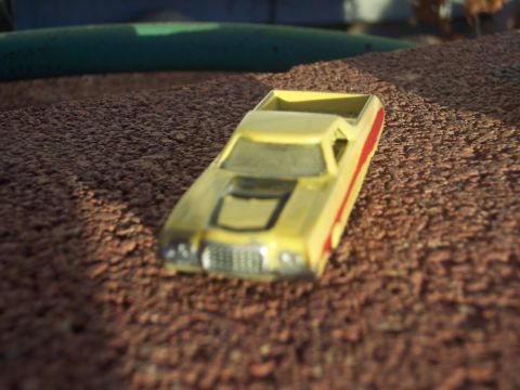 1972 Ford Ranchero - A yellow toy 1972 Ford Ranchero with a red stripe sits on a textured surface.