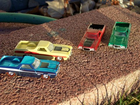 1972 Ford Ranchero - Collection of toy cars, including two that resemble Ford Rancheros, displayed outdoors.