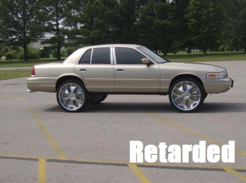 2000 Mercury Grand Marquis - A gold sedan with oversized chrome wheels is parked in a lot, with text overlaid on the image.
