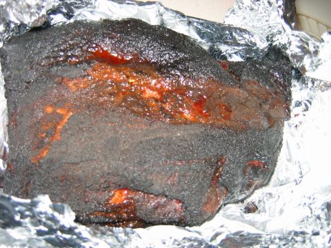 1992 Ford Bronco - A piece of smoked meat, likely brisket, is wrapped in aluminum foil.