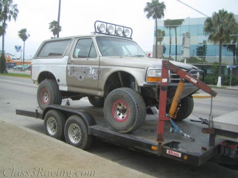 1986 Ford Bronco - A modified Ford Bronco is transported on a trailer, off-road modifications and a custom paint job.