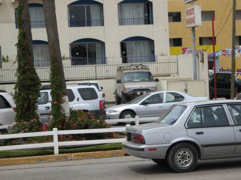 1986 Ford Bronco - A modified silver van with off-road lights and a custom bumper is parked in front of a building.