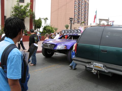 1986 Ford Bronco - A custom off-road truck is parked on a street, with a dark green SUV in the foreground.