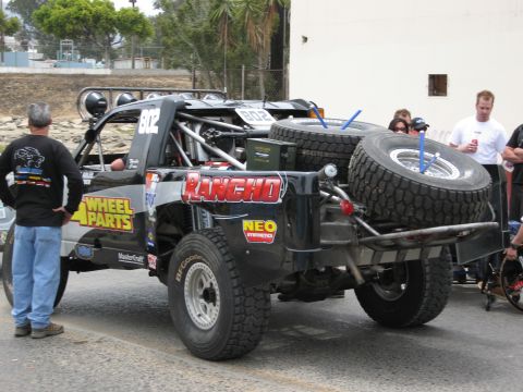1986 Ford Bronco - A modified off-road truck with racing decals and spare tires is parked outdoors.