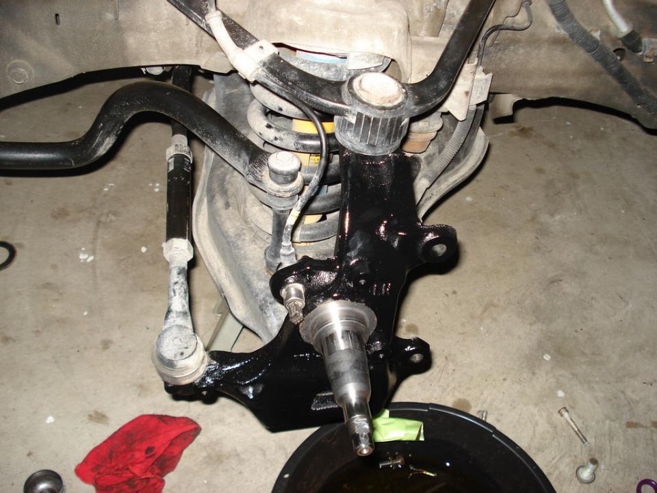 Close-up of a black painted suspension knuckle with tie rod end and sway bar link attached