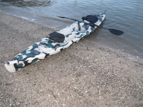 1991 Ford Bronco - Kayak with camouflage pattern sits on the shore, paddle nearby.
