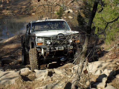 1986 Ford Bronco - Modified Ford Bronco driving over rocks on a trail.