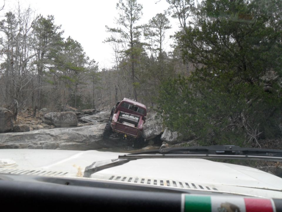 1986 Ford Bronco navigating a rocky trail, viewed from inside another vehicle