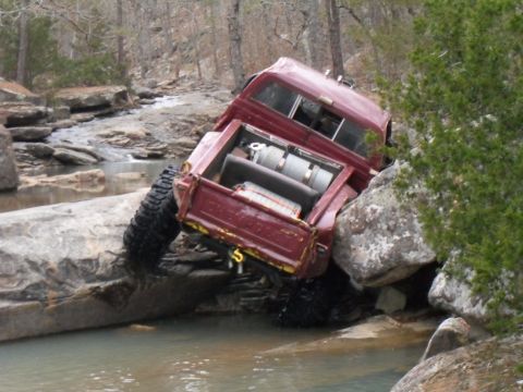 1986 Ford Bronco - This off-road vehicle appears to be stuck while navigating a rocky stream bed.
