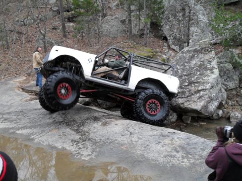 1986 Ford Bronco - A modified white off-road vehicle navigates a challenging rocky obstacle course.